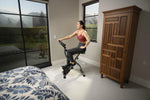 Woman exercising on a stationary bike in a bedroom with a wooden wardrobe.