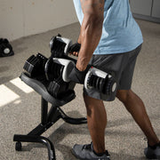 Person lifting Ativafit adjustable dumbbells on workout stand in home gym