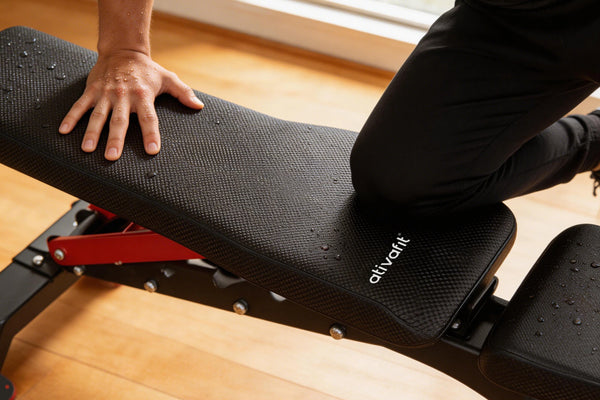 Person using a adjustable weight bench with 'ativafit' branding on a wooden floor.