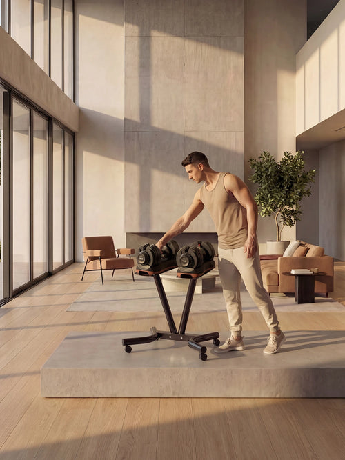 Man arranging dumbbells on a stand in a modern indoor setting