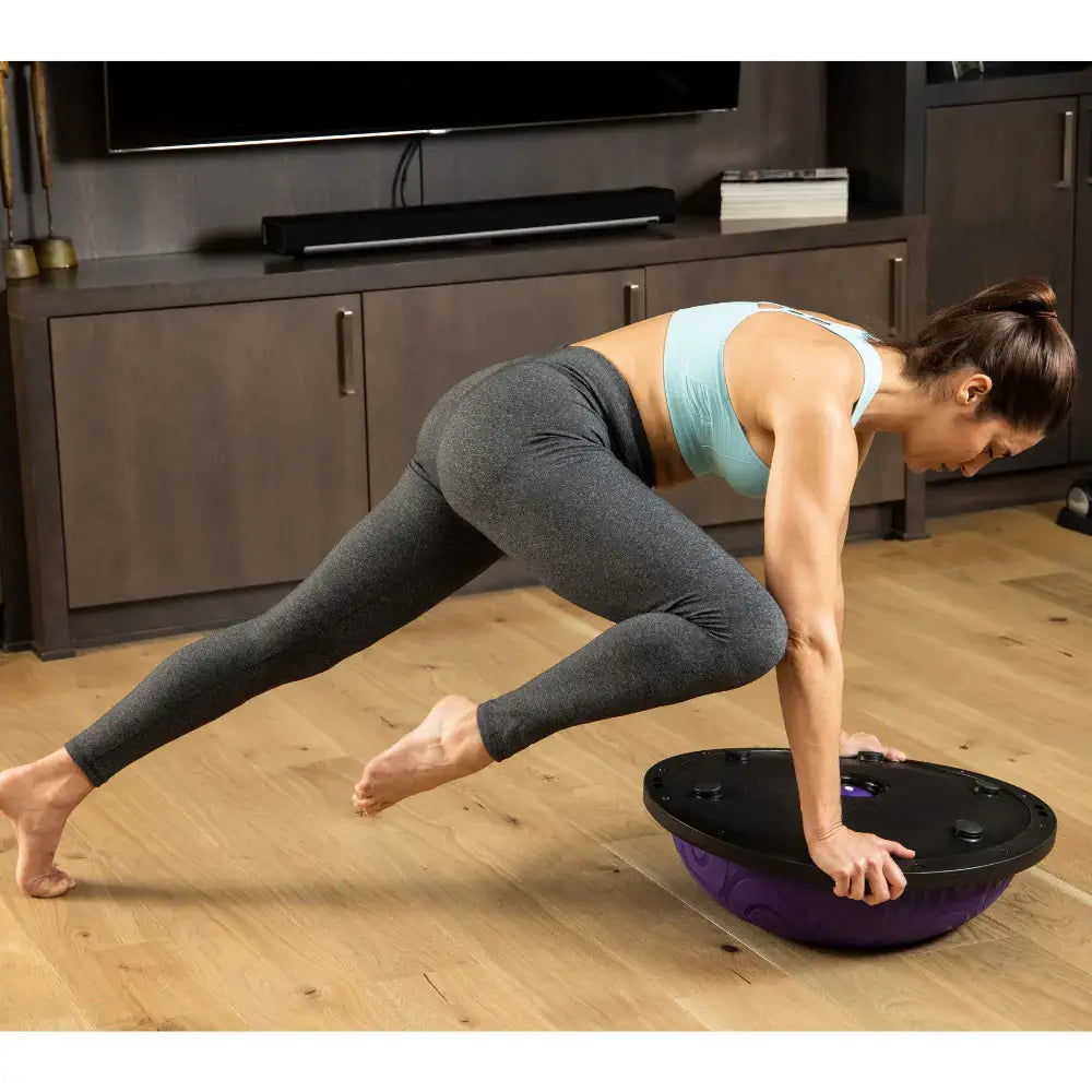 Woman using purple Half Ball Balance Trainer for mountain climbers. Boosts core strength, balance, and agility in home workouts.