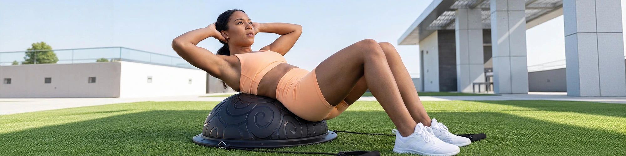 Woman exercising on a Bosu ball outdoors with a modern building in the background