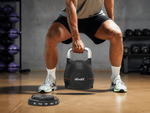 Person performing a squat with a kettlebell in a gym setting