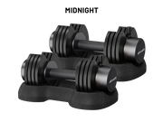 Two black adjustable dumbbells with weight plates on a matching black stand, shown on a white background with the text 'MIDNIGHT' above them. The brand name 'olivakt' is visible on the dumbbell ends.