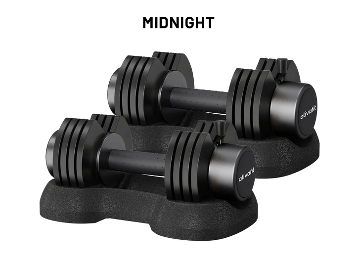Two black adjustable dumbbells with weight plates on a matching black stand, shown on a white background with the text 'MIDNIGHT' above them. The brand name 'olivakt' is visible on the dumbbell ends.